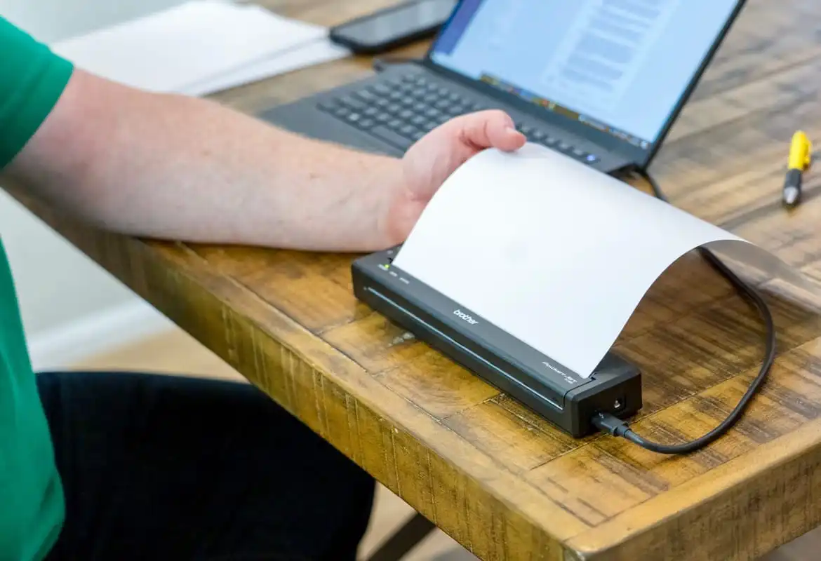 Field worker printing a document from a notebook computer to a PJ series mobile printer while sat at a desk