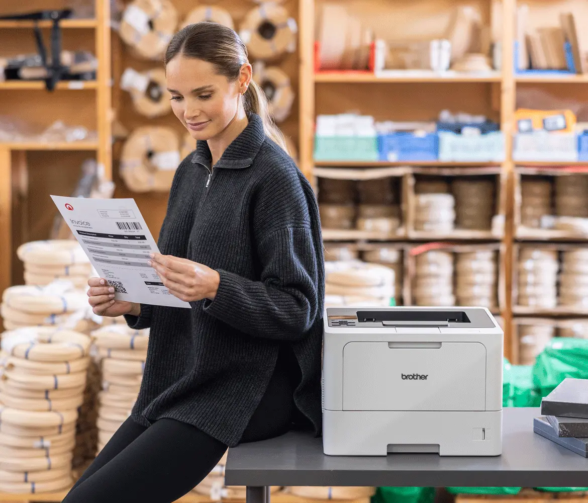 A woman sat reading a delivery note next to a Brother printer