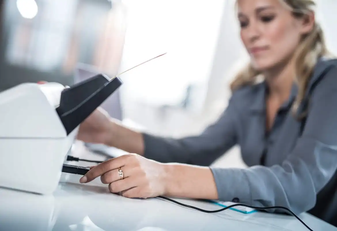 A business woman inserting a USB flash drive into the rear of a Brother ADS-2700 multiple page scanner