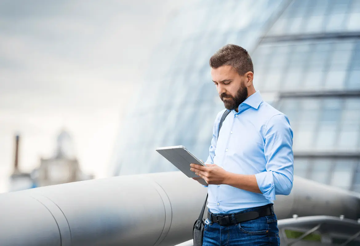 A businessman looking at a tablet device while standing on an office rooftop terrace