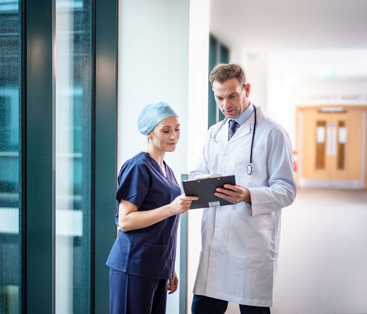 Male doctor in white coat and stethoscope with female doctor in corridor of hospital
