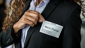 A businesswoman sticking a visitor pass to her suit jacket