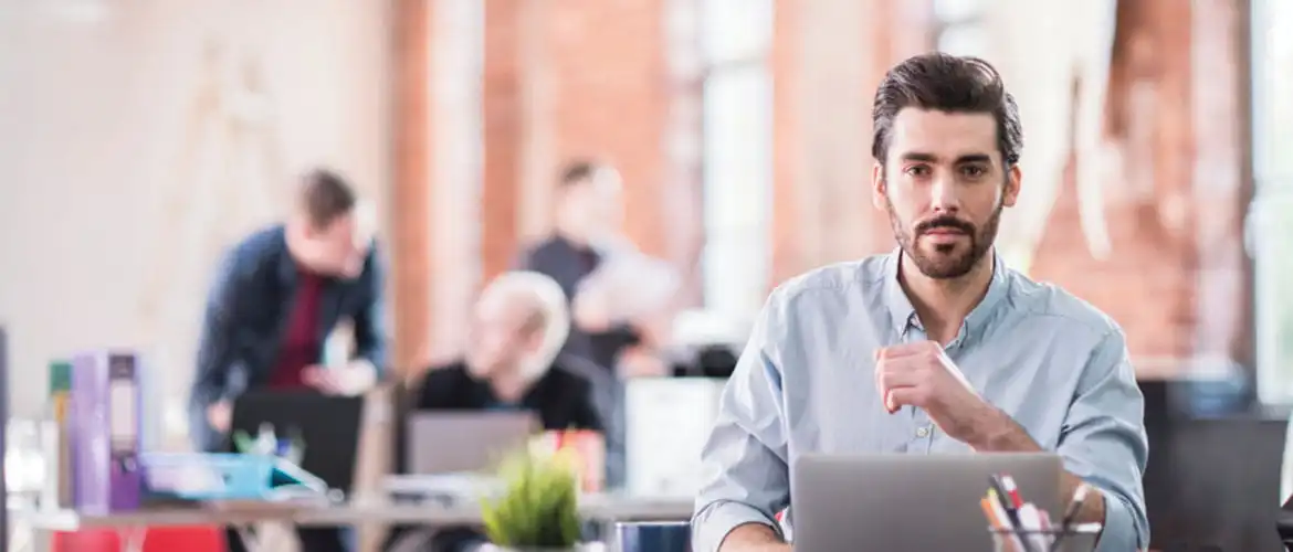 homme assis à son bureau devant un ordinateur portable