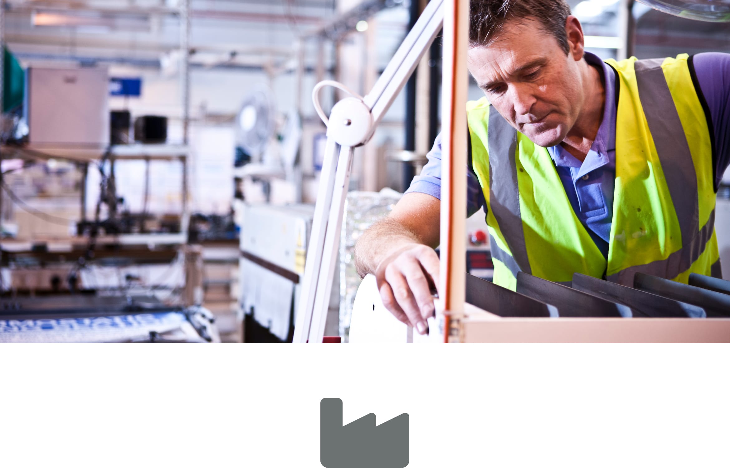 A male factory worker wearing a high visibility vest operating machinery