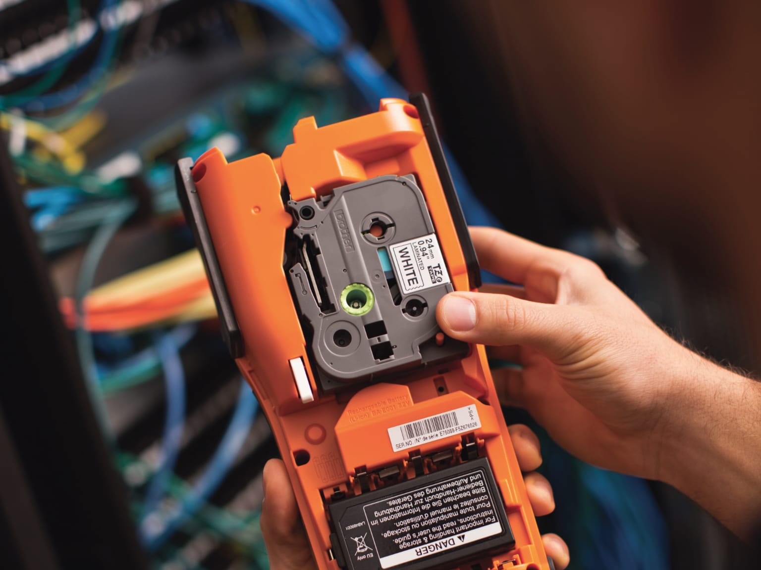 Electrician installing tape into a PT-E550 label printer with electrical cabling in the background