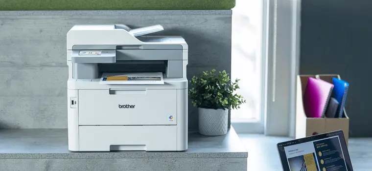 Brother MFC-L8340CDW laser printer sat on a desk whilst printing out a document