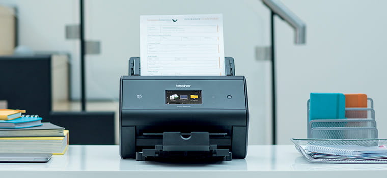 Scanner de documents de bureau Brother ADS-3600W sur le bureau avec des ordinateurs portables