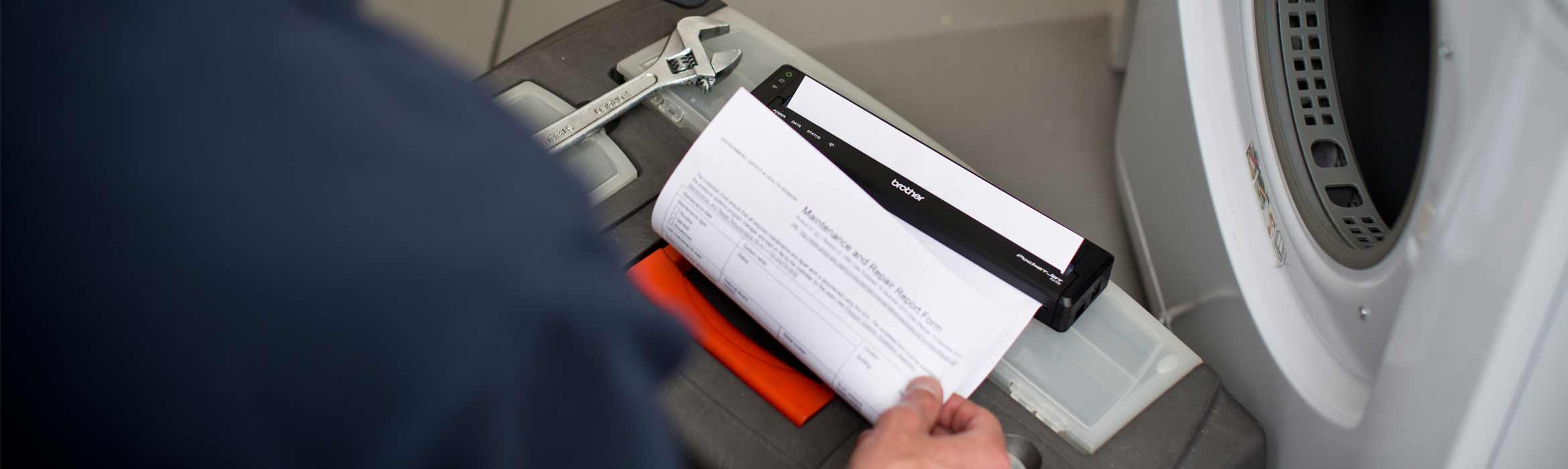 Man holding a Brother Pocket Jet mobile printer next to a washing machine