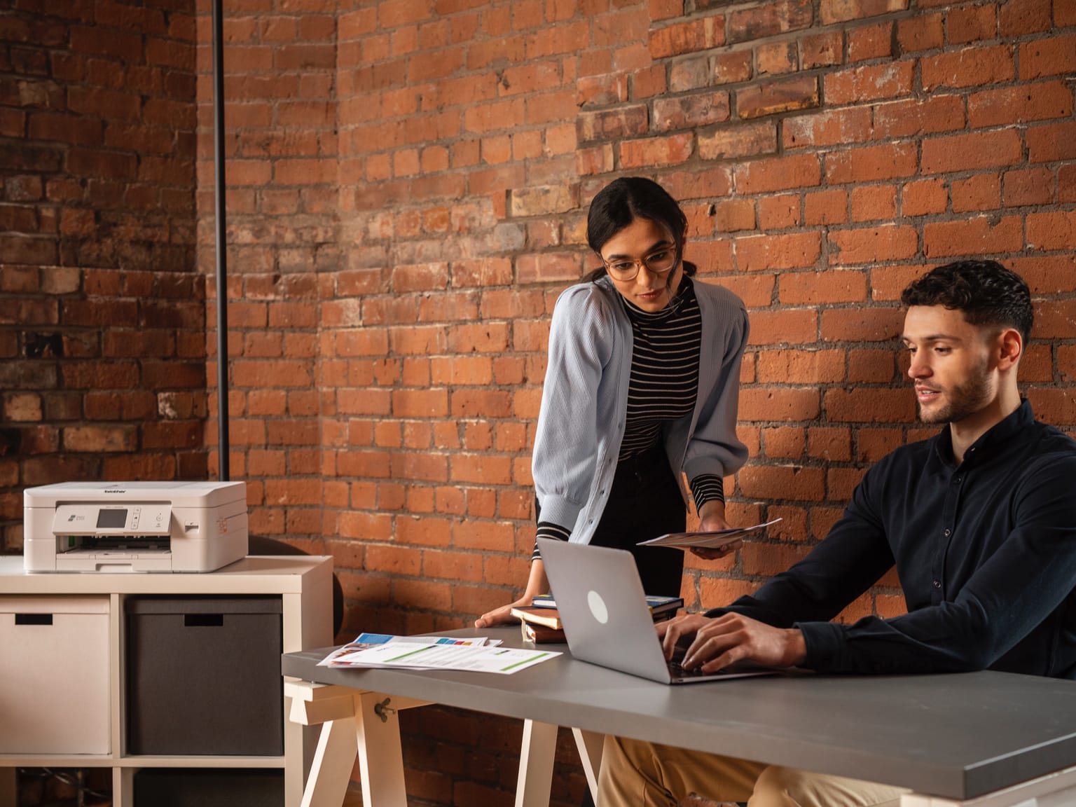 Male and female colleagues connecting a printer to a Wi-Fi network in a small office environment