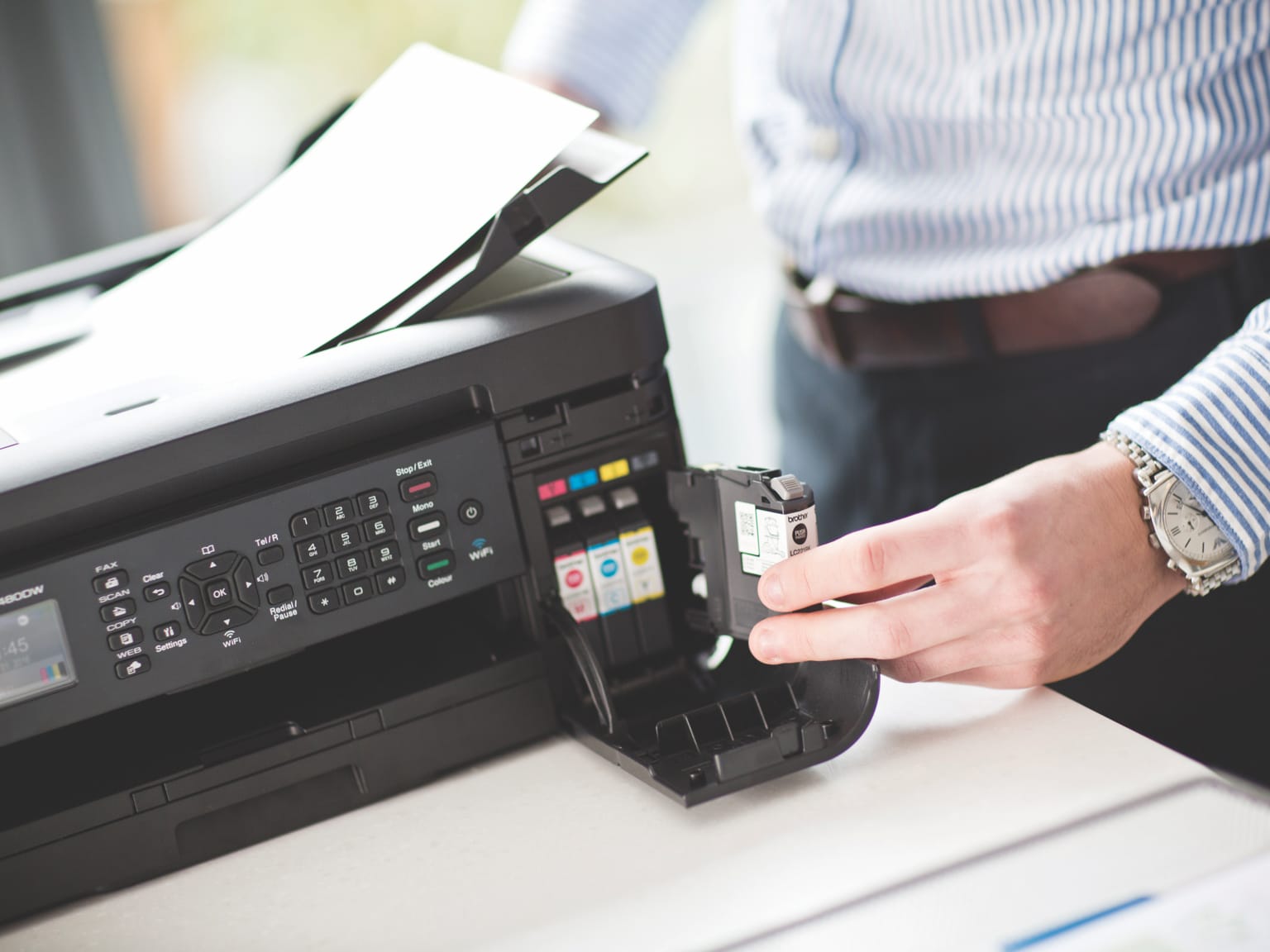 A man changing an ink cartridge in a Brother inkjet printer