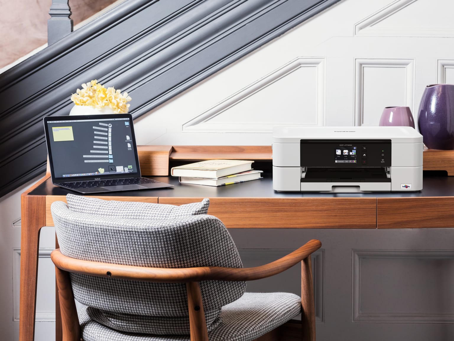 Home office desk with notebook computer and printer in front of wood panelled staircase