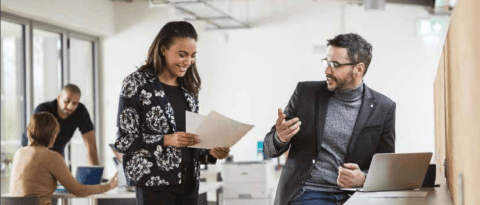 Two colleagues in an office discussing something on printed paper