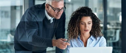 Shot of two business people working late on a laptop in an office
