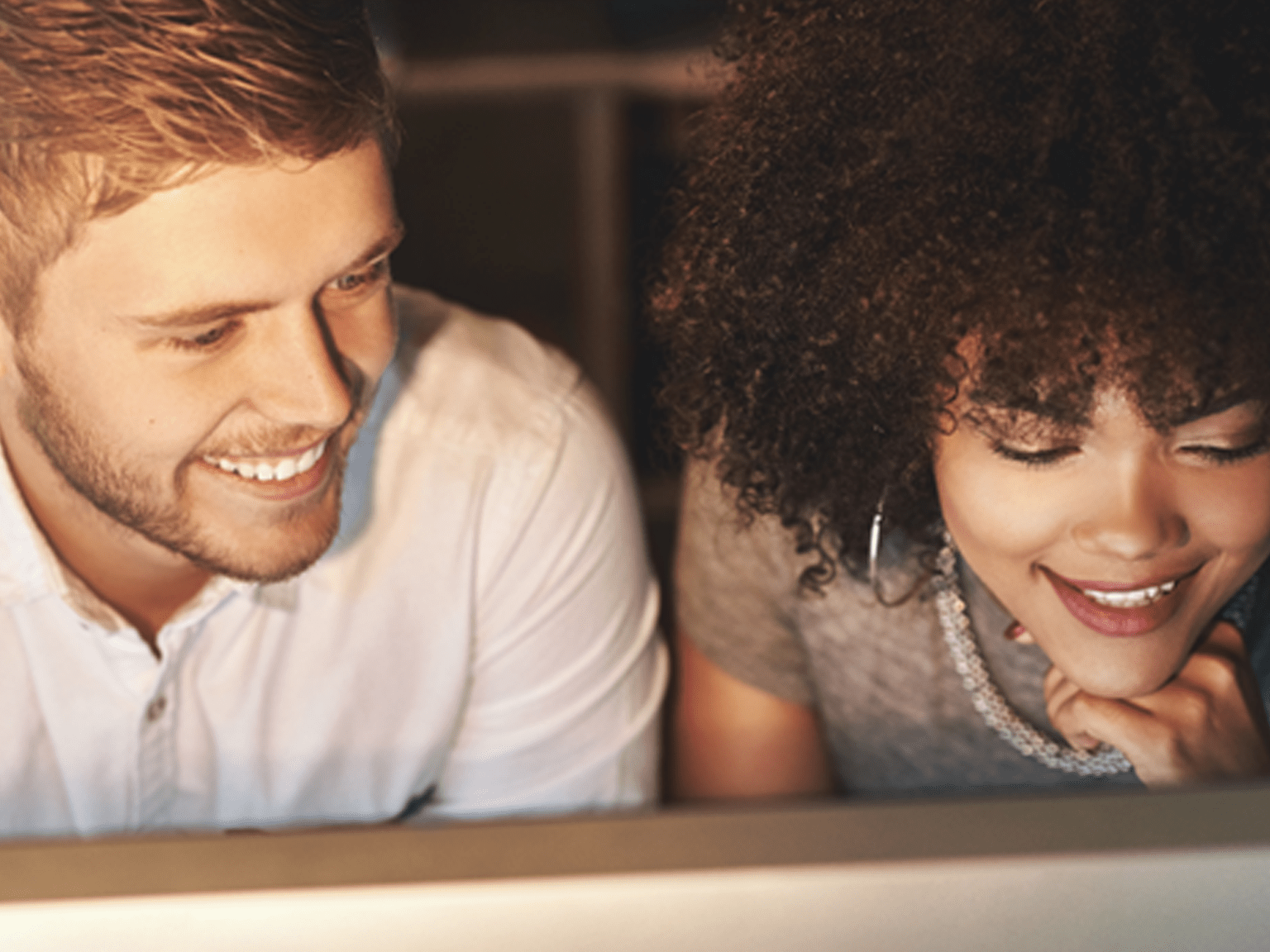 Man and woman smiling while looking at something out of shot