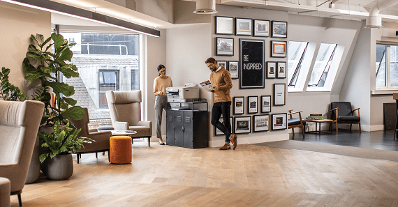 Man and woman standing by Brother printer, looking at printouts