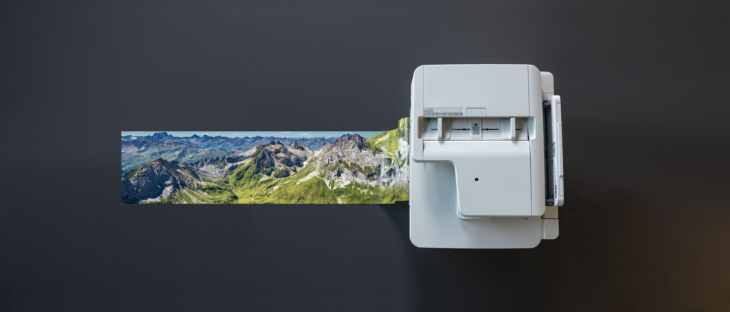 Bannerdrucker von Brother druckt Hochglanzfoto mit Drucker auf schwarzem Hintergrund.