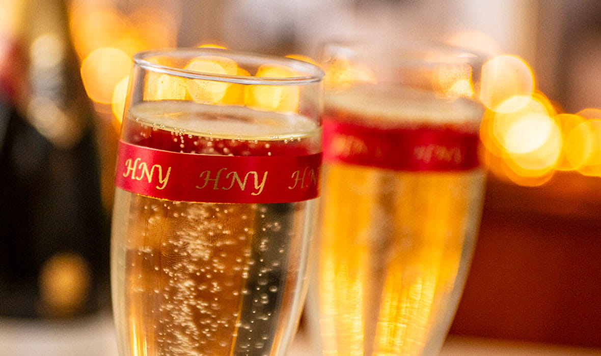 Zwei ChampagnerFlöten, Umhüllt von EIEM TextilSchriftband mit dem Text 