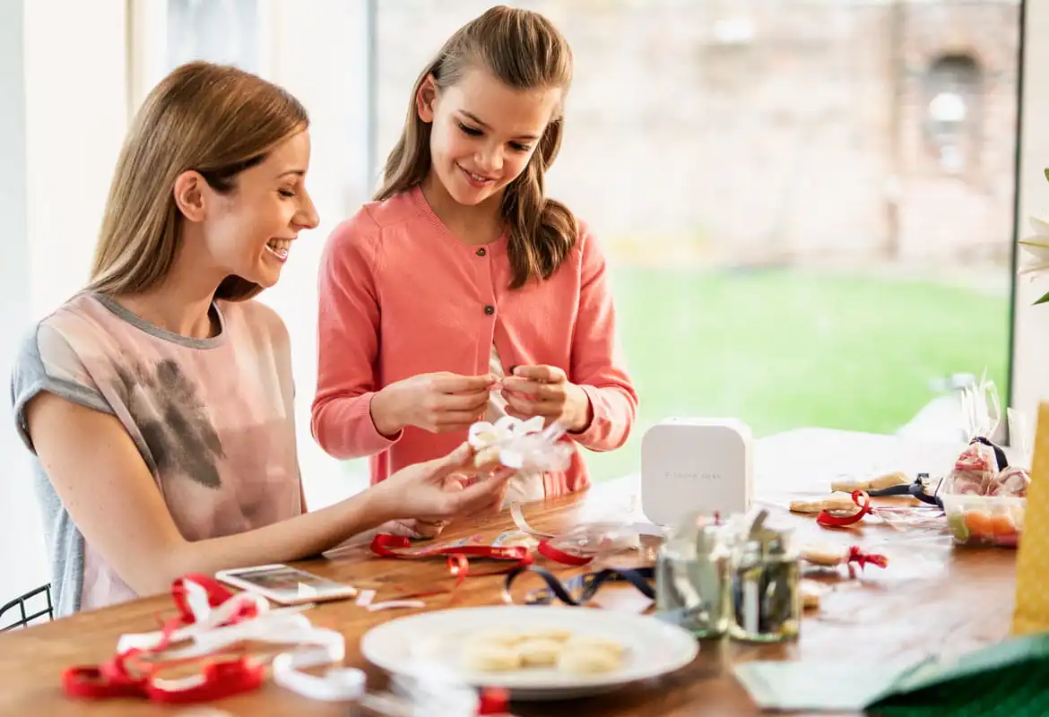Mutter und Tochter mit dem Brother P-Touch Cube Label und den Ribbon-Drucker, um Gegenstände zu Hause zu basteln