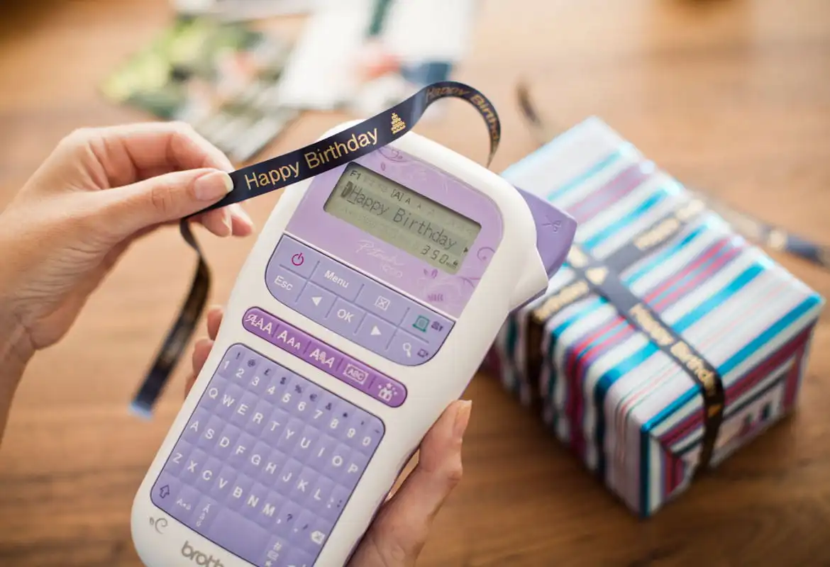 Ein Brother P-Touch H200-Label und der Ribbon-Drucker wird verwendet, um ein glückliches Geburtstagsband für die Geschenkverpackung zu erstellen