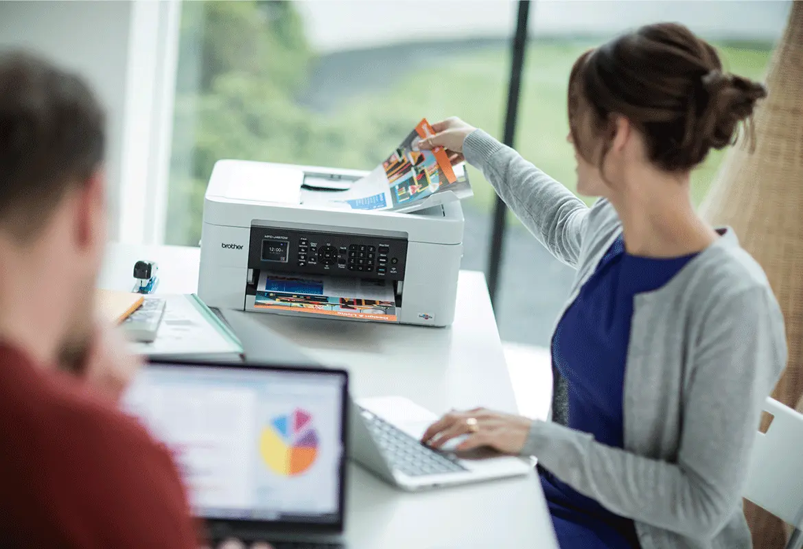 Eine Frau sitzt an einem Brother Multifunktionsdrucker und kopiert etwas.