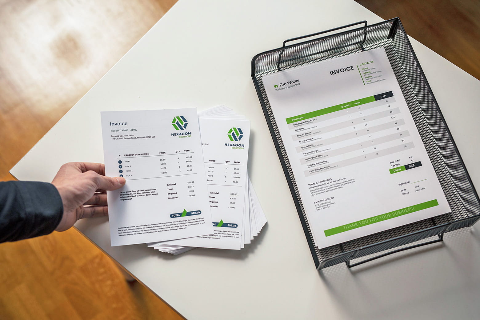 Hand hält Rechnungen, geschnitten im A5-Format, Ablage daneben