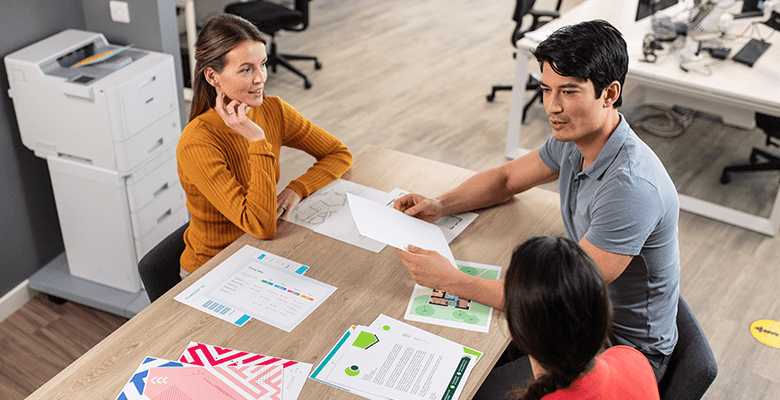 Three colleagues having a discussion while sat around a table in an office environment