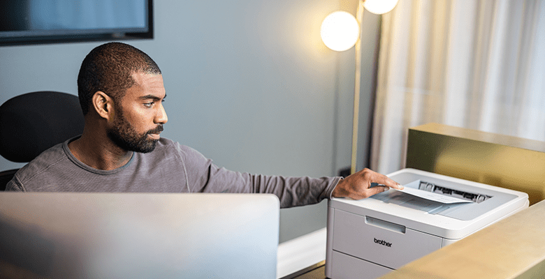 A man printing a document while sat at a desk in an SMB environment