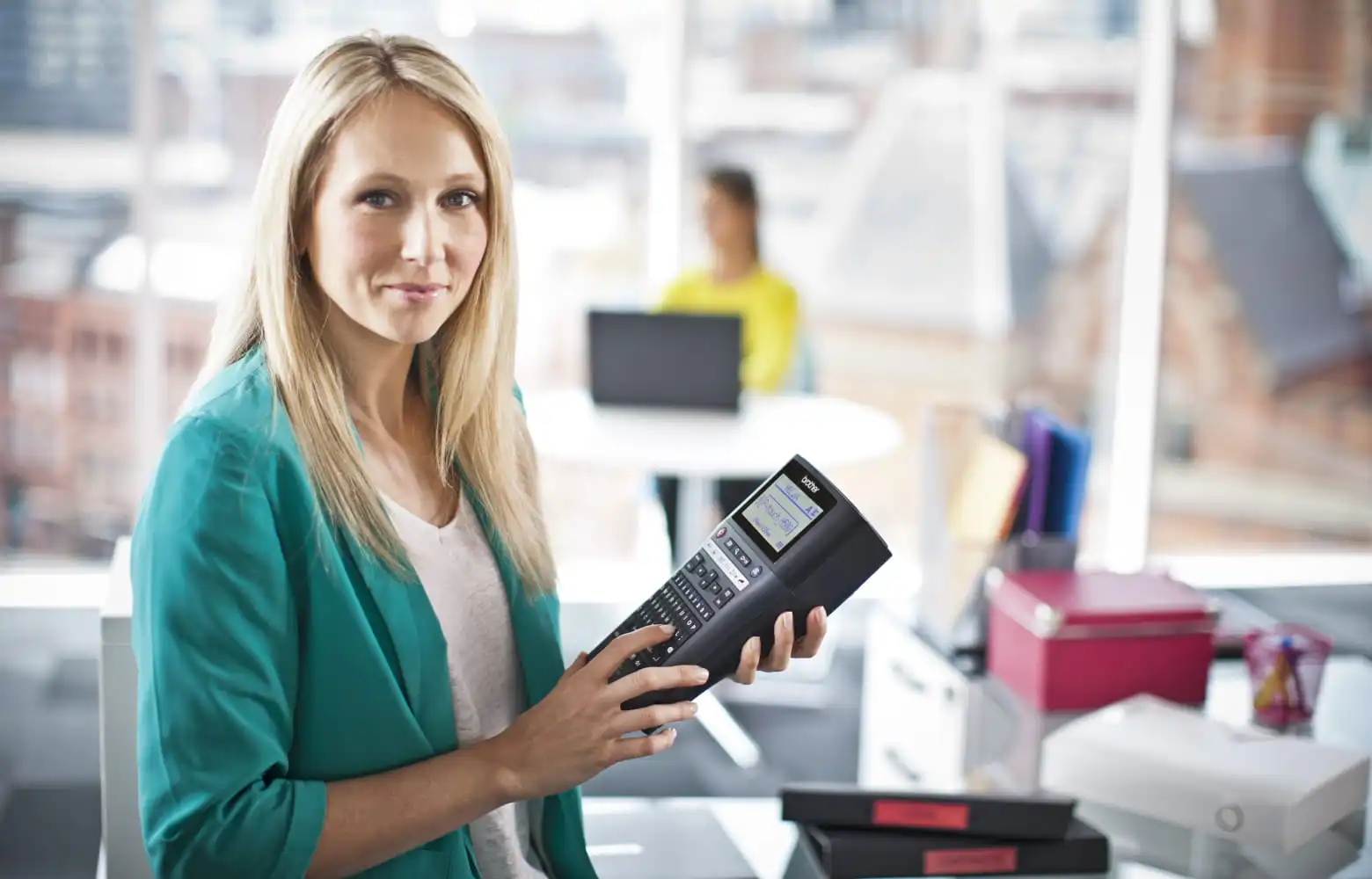 Female facilities manager holding a Brother P-touch label printer in preparation for labelling items around the office