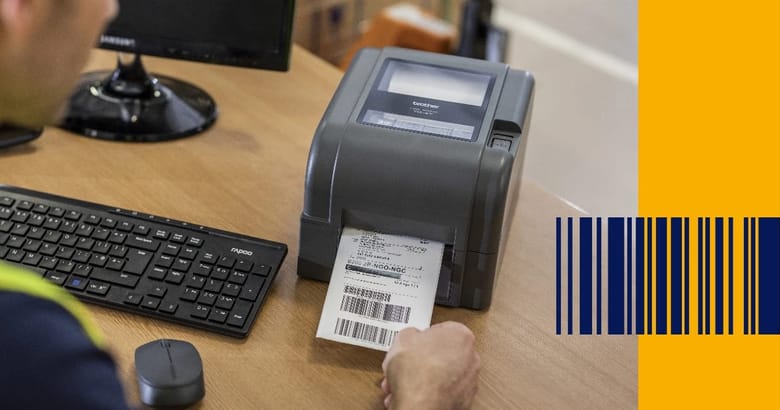 A warehouse worker wearing a high visibility vest removing a barcode label from a Brother TD series label printer