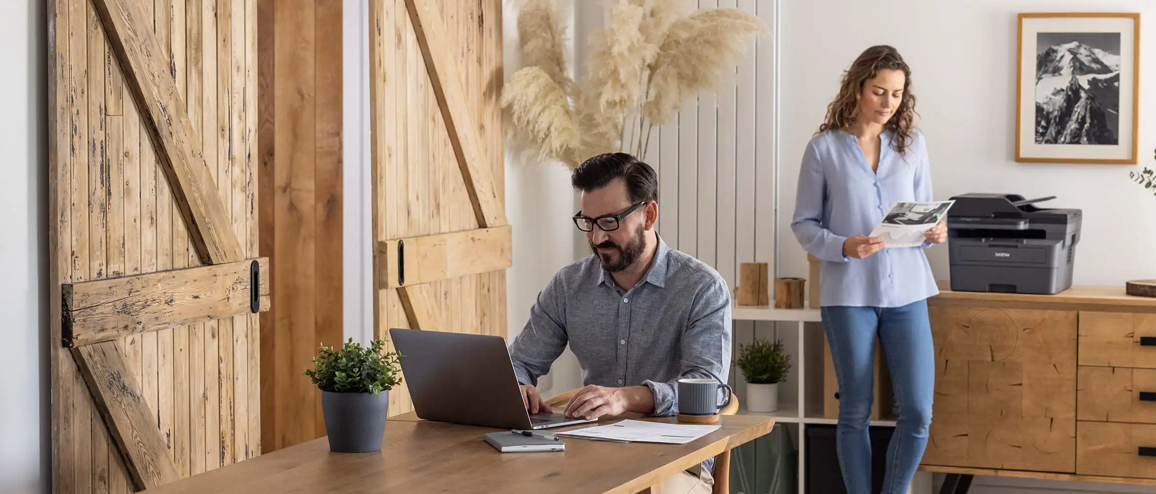 A man and woman in a home setting with a Brother printer sat on a sideboard